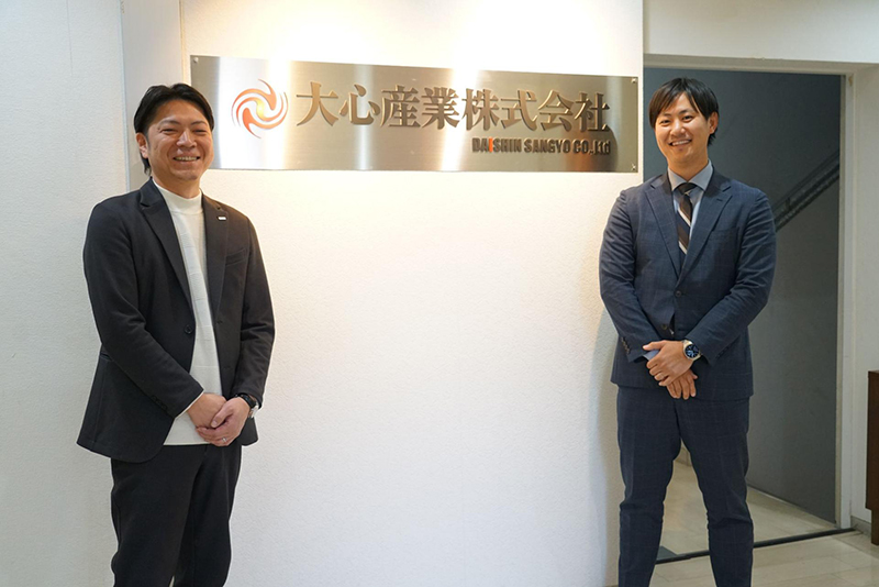 大心産業株式会社のエントランスで笑顔を見せる専務取締役の小野様と白石担当者