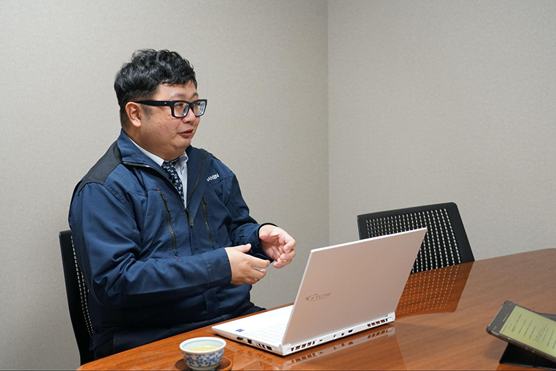ノートパソコンを前に、身振りを交えて導入の経緯とメリットを語る三信産業株式会社の佐藤様
